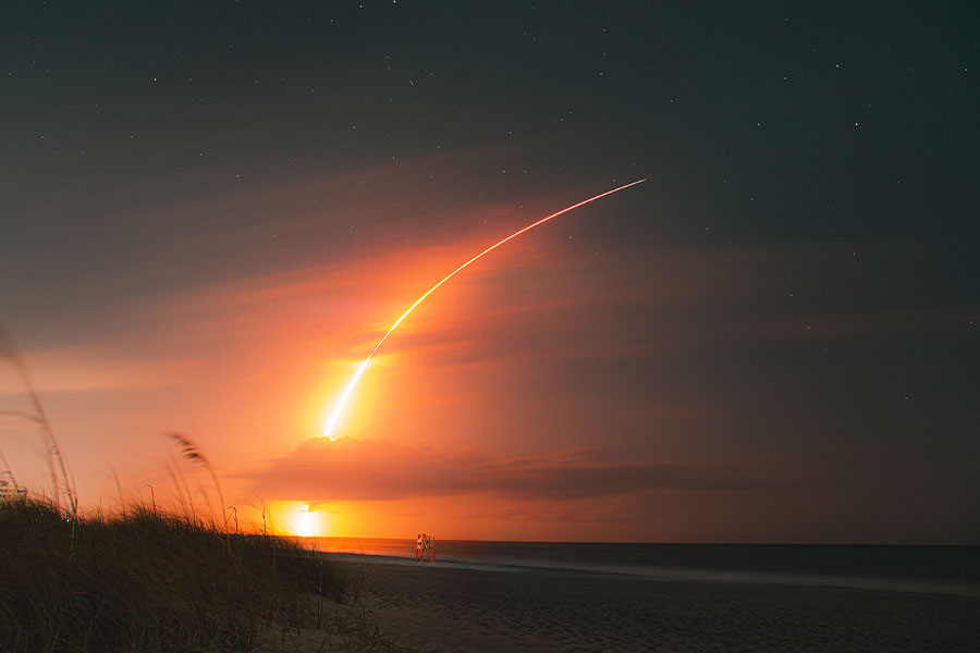 a space launch in the night over the beach
